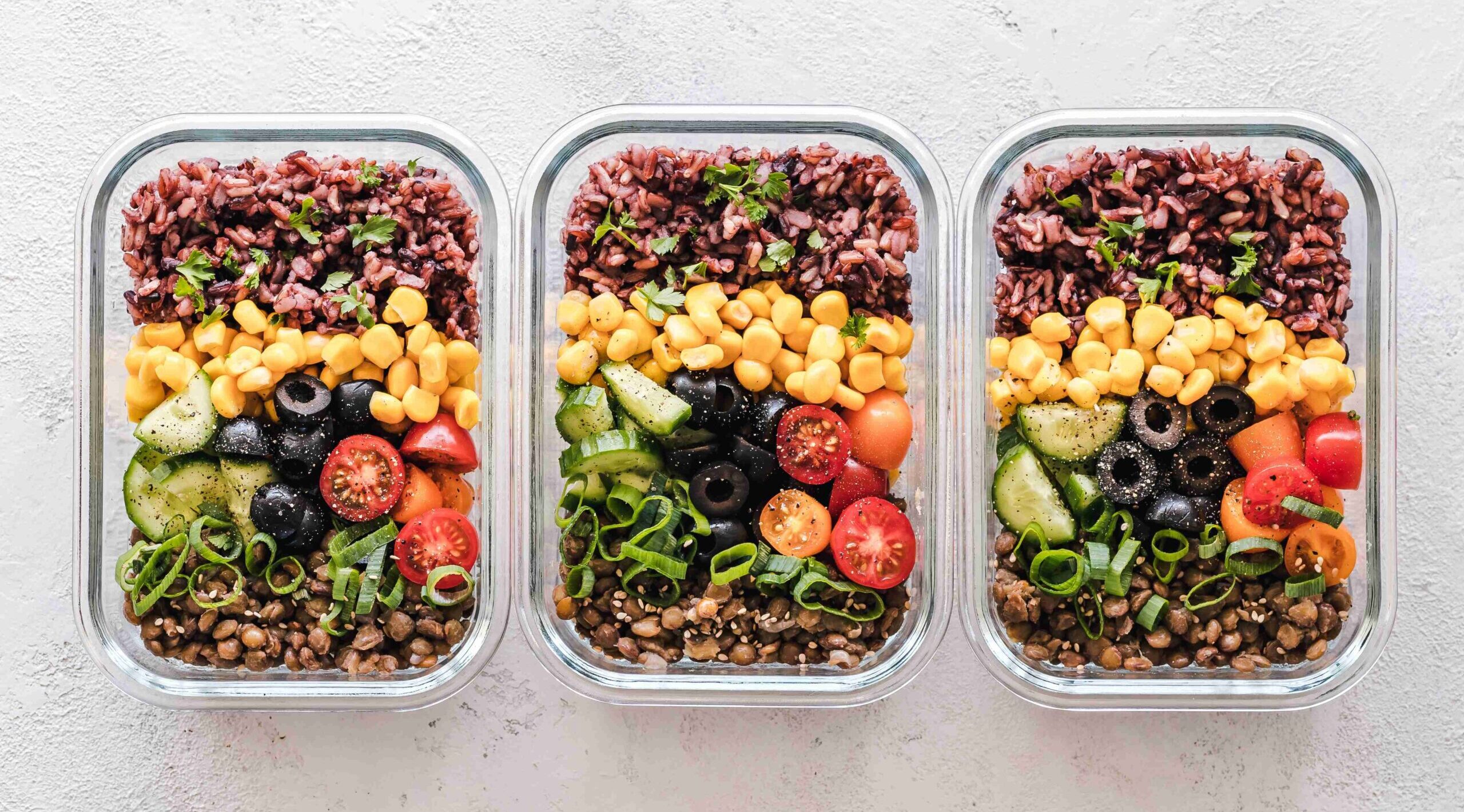 Three meal containers with beans and fresh vegetables