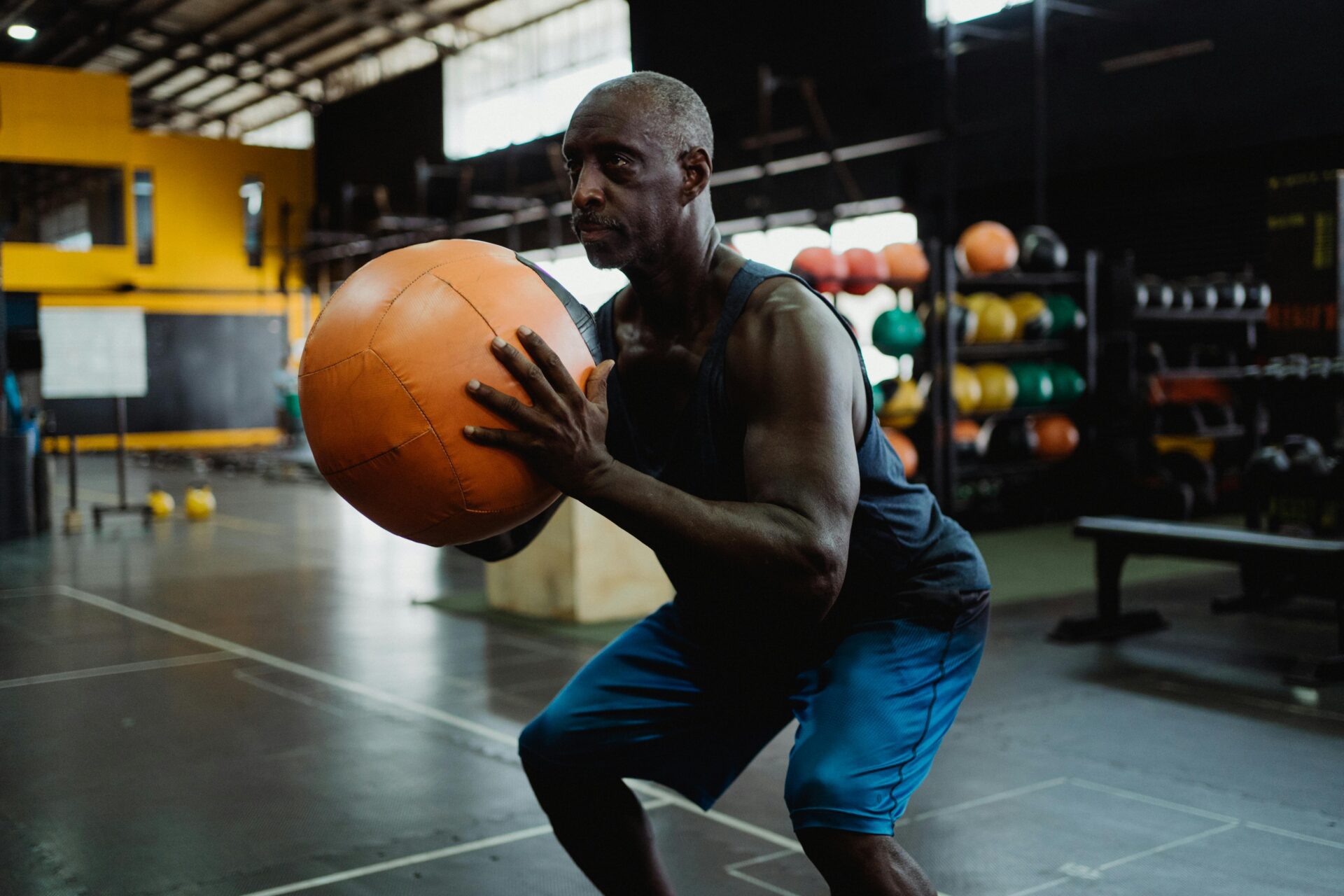 Older man performing a squat with a medicine ball. 
