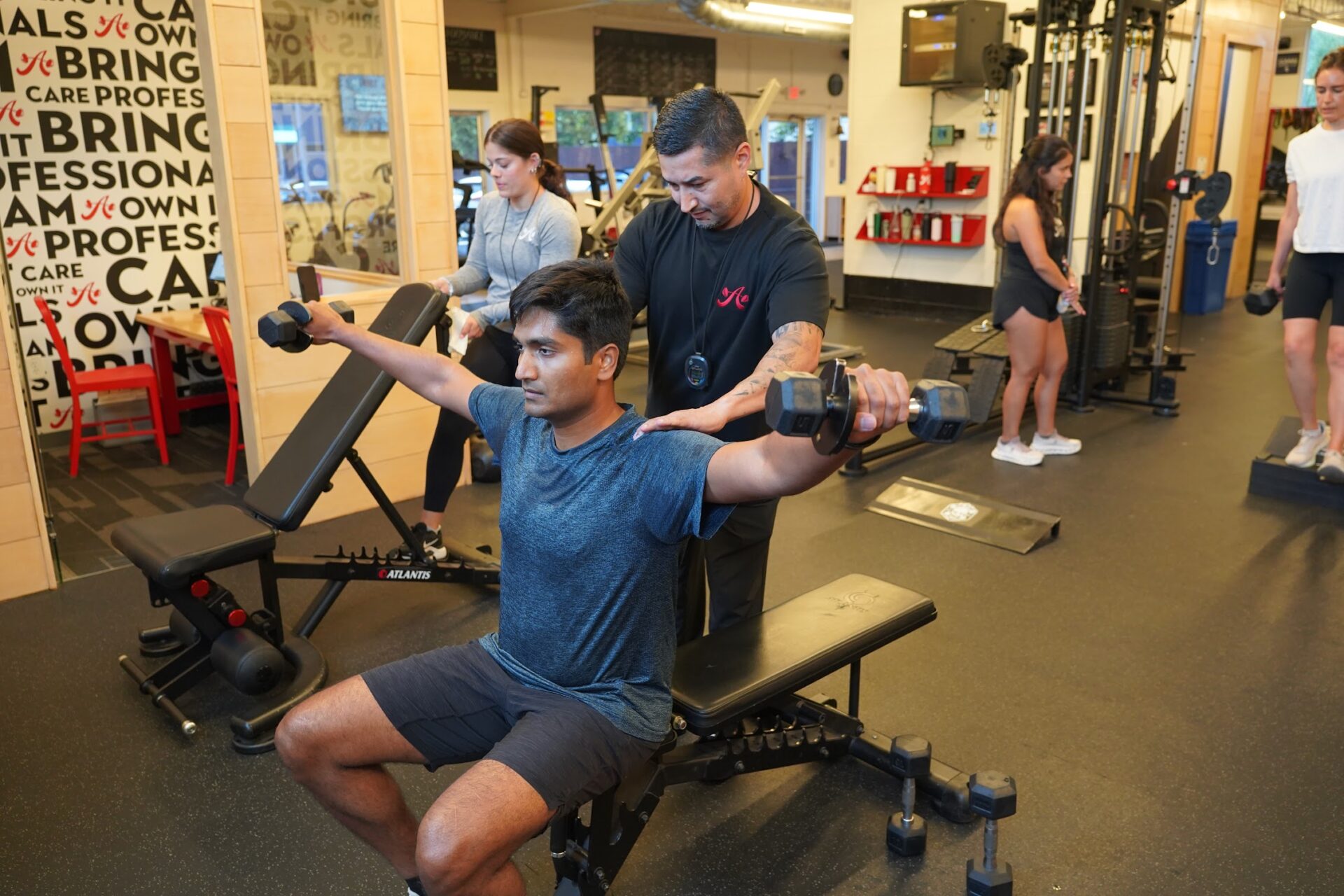 A personal trainer with a client doing lateral raises